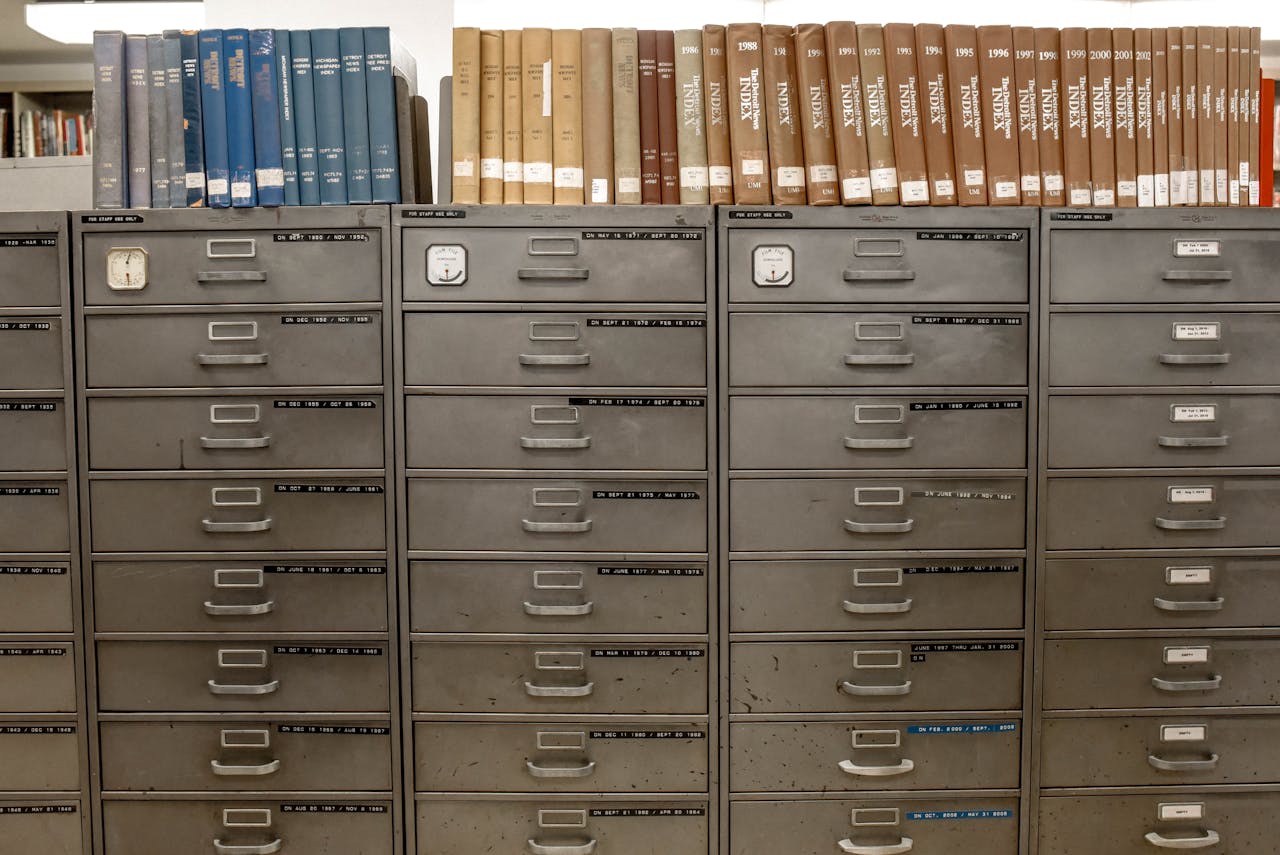 about-us Organized filing cabinets stacked with indexed books in a library setting.